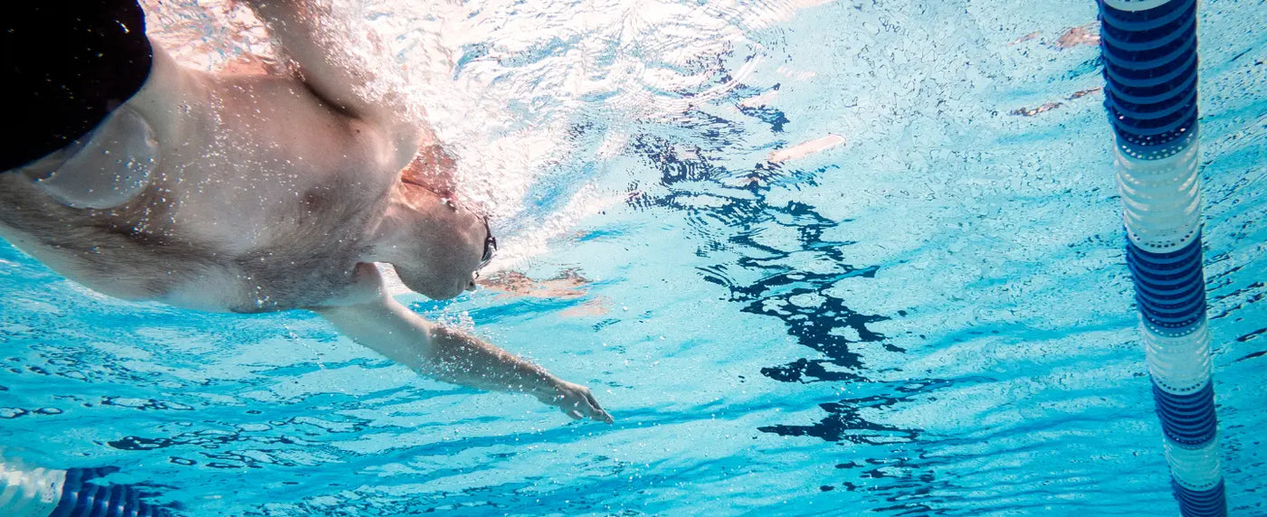 Schwimmender Mann im Wasser mit teilweise sichtbarem Stoma-Beutel