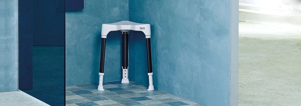 Duschhocker TAYO B-Protect von Dietz in dreieckiger Ausführung, platzsparend in der Ecke einer bodengleichen Dusche platziert – modernes, hygienisches Badezimmerdesign.